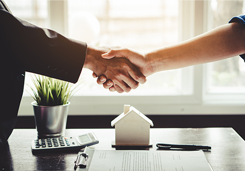 shaking hands over clipboard on desk