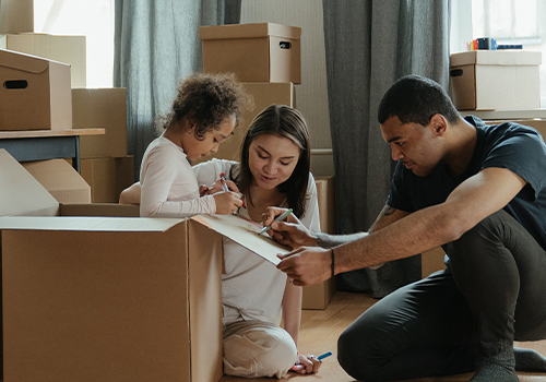 child in a brown box drawing with parents