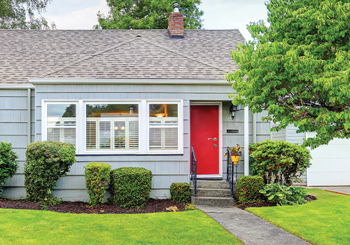 front steps of small home with red door and grey shingled roof