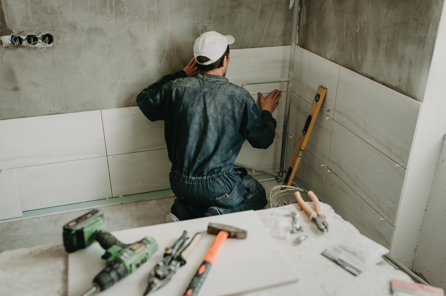 Construction worker installing tiles on bathroom wall