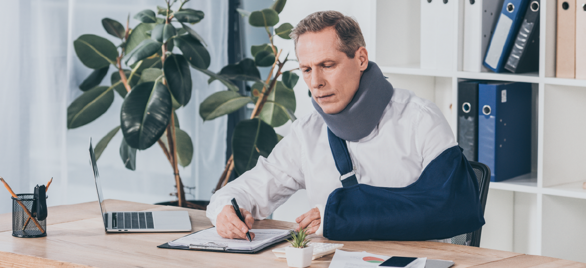 Employee Fake Injury - Man at desk with arm cast and neck brace