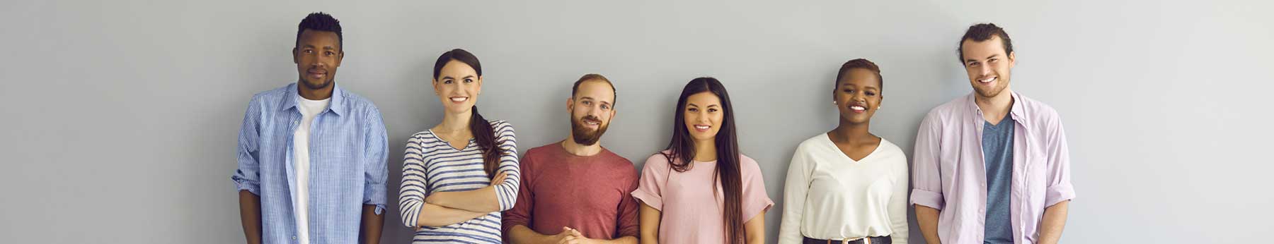 group of people standing against white wall smiling