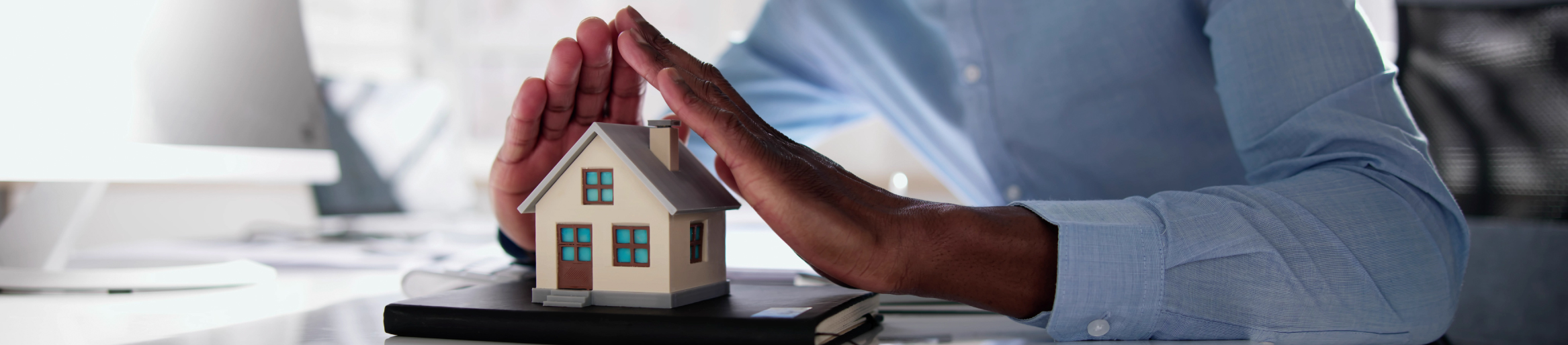 Man using hands to protect small model of a home, demonstrating "coverage"
